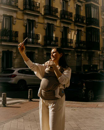 Madre usando una mochila portabebés Babiini
